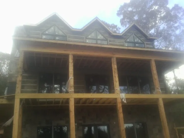 Dormers and porch framing on a large log home under construction — Roof Coating work by our crew in Lyons