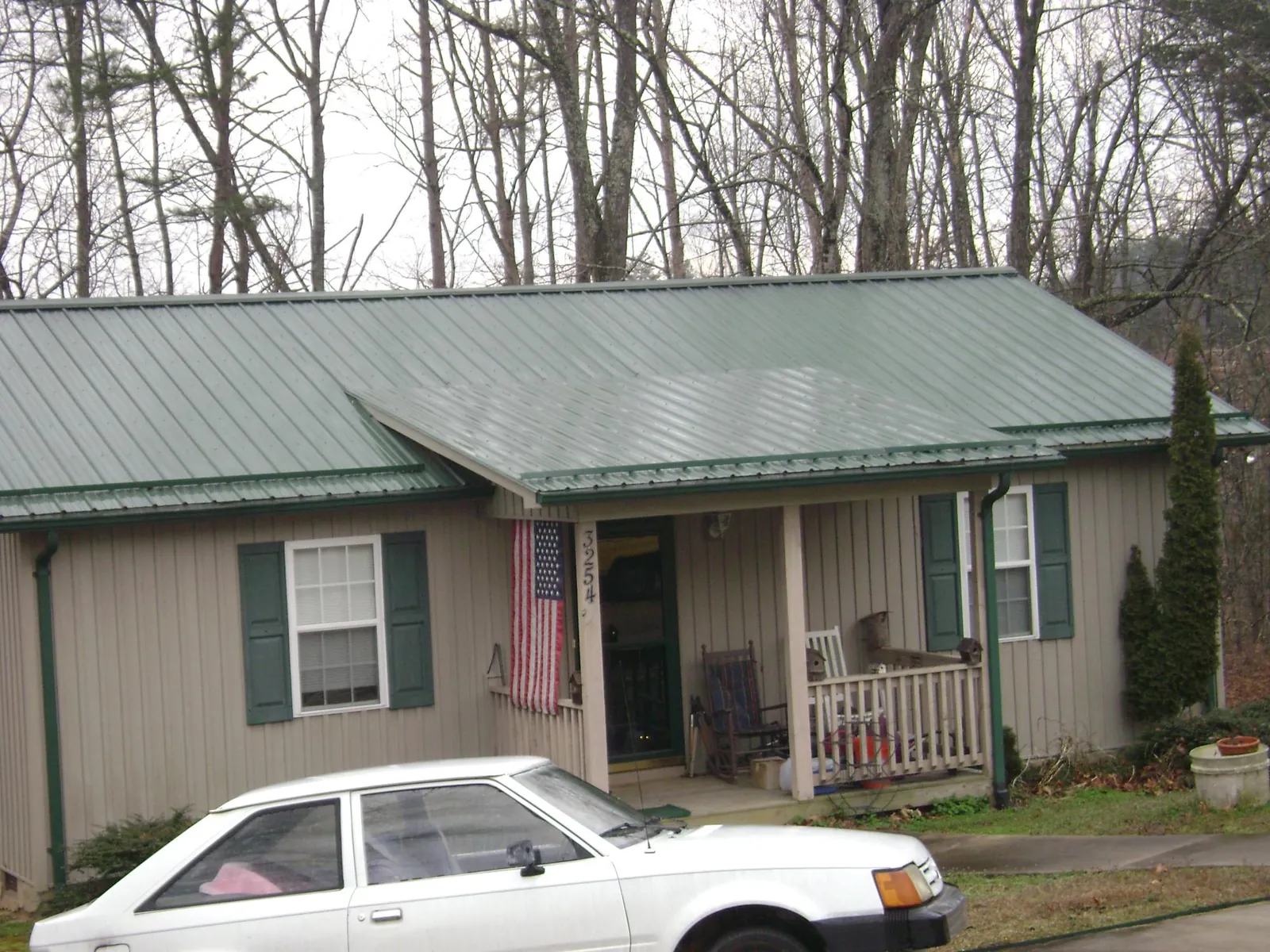 Green metal roof and front porch on a tan sided cottage in Lyons